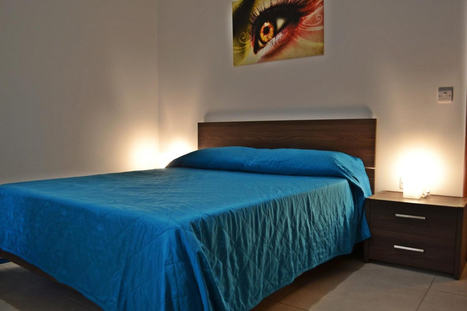 Double bedroom centred view with bedside lamps and framed artwork